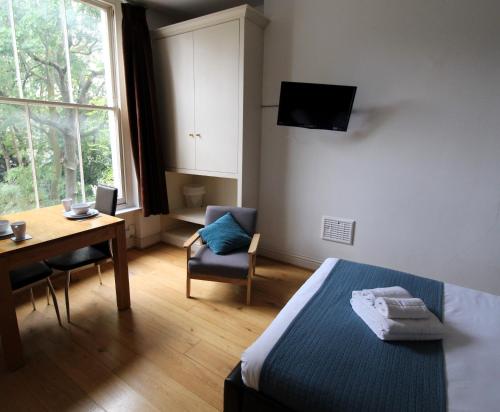 a bedroom with a bed and a table and a desk at Longridge Road Apartments By Viridian Apartments in London