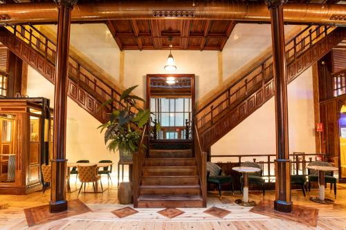a lobby with a staircase and tables and chairs at Hotel Las Tres Campanas in Badajoz