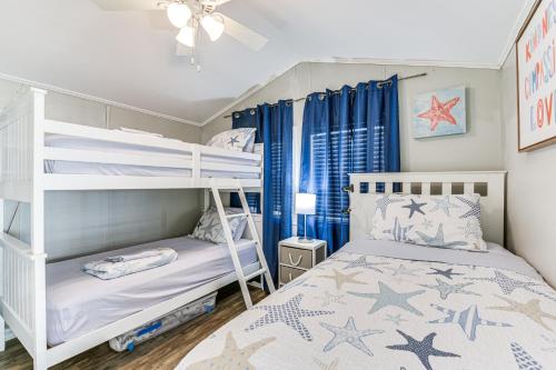 a bedroom with two bunk beds and blue curtains at Bright Miramar Tropical Cabana, 2 Blocks to Beach! in Destin