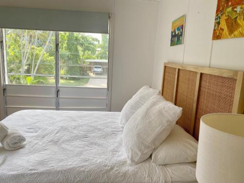 a bedroom with a bed with white sheets and a window at The Beach House at Pallarenda in Pallarenda