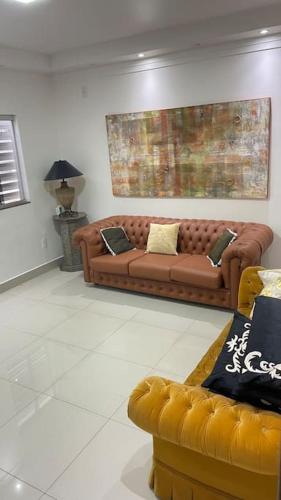 Casa próximo do aeroporto de Brasília في برازيليا: غرفة معيشة مع كنب بني في غرفة