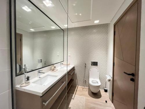 a bathroom with a toilet and a sink and a mirror at Palace Dubai Creek Harbour Residences Skyline Apartment in Dubai