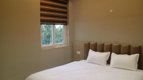 a bedroom with a bed with white sheets and a window at 2nd Home - Smart in Tājganj