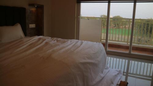 a bed with a white comforter in front of a window at 2nd Home - Smart in Tājganj