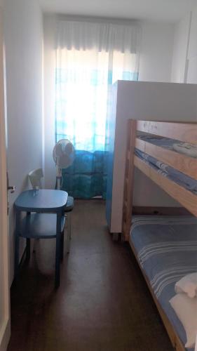 ein Schlafzimmer mit einem Etagenbett, einem Tisch und einem Schreibtisch in der Unterkunft Viale Dante in Grado