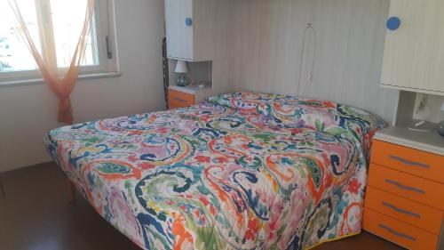 ein Bett mit farbenfroher Bettdecke in einem Schlafzimmer in der Unterkunft Viale Dante in Grado