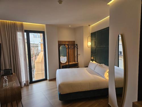 a hotel room with a bed and a large window at Hotel Las Tres Campanas in Badajoz