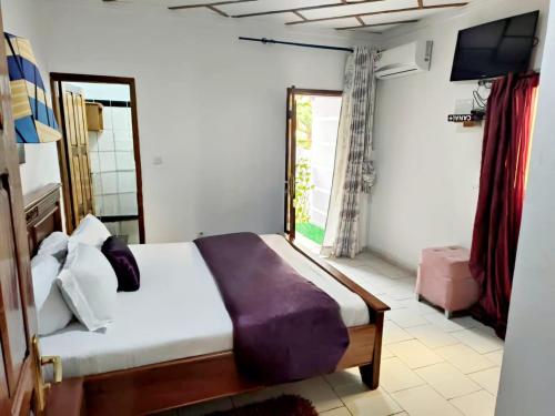 1 dormitorio con 1 cama grande y TV en GOLF HILLS BASTOS, en Yaoundé