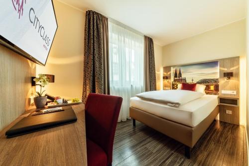 a hotel room with a bed and a desk at CityClass Hotel am Heumarkt in Cologne