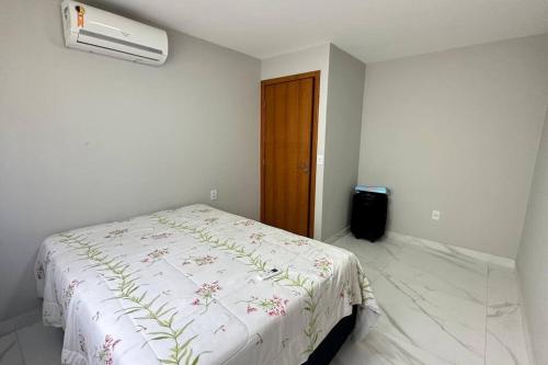 a bedroom with a bed with a white blanket with flowers at Casa Retiro do Congo in Vila Velha