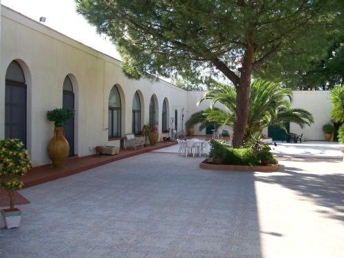 a courtyard with a tree and chairs and a building at Agriturismo Fiori d'Arancio in Palagiano