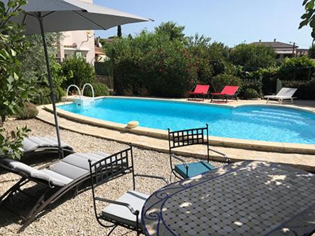- une table et des chaises avec un parasol à côté de la piscine dans l'établissement Résidence méditerranéenne, piscine, jardin pour 6 personnes, à Roujan