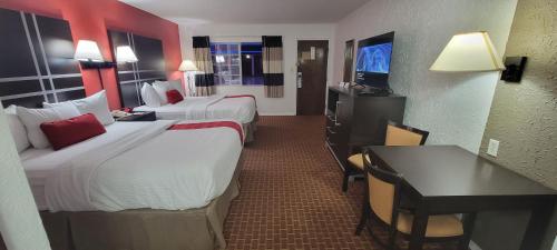 a hotel room with two beds and a desk at Ramada by Wyndham Mountain Home in Mountain Home