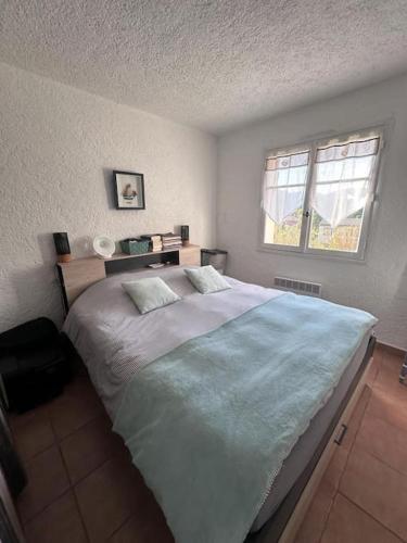 une chambre avec un grand lit et une fenêtre dans l'établissement Appartement Le Castillon, à La Garonnette-Plage