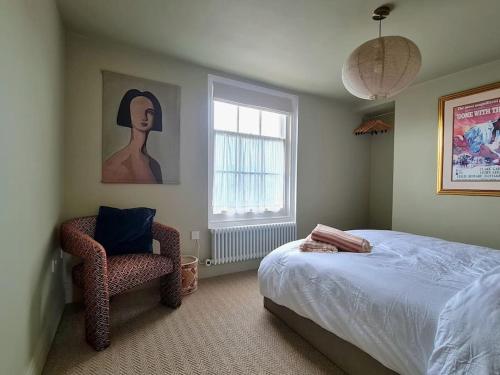 um quarto com uma cama, uma cadeira e uma janela em Trinity Square Loft + sea views em Kent