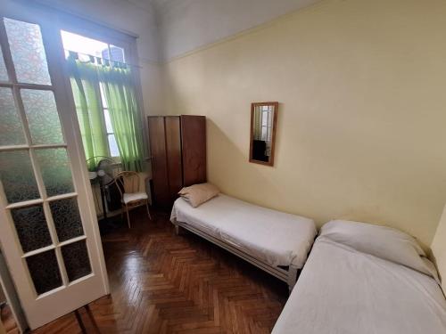 a room with two beds and a mirror on the wall at Aires de Tango Hostel in Buenos Aires
