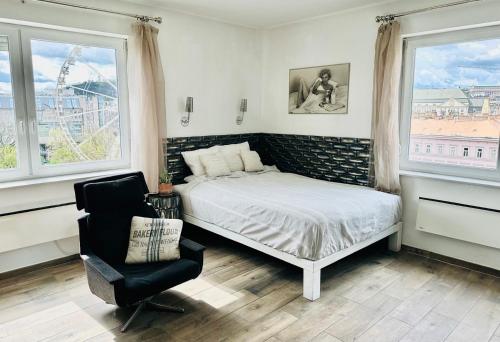 a bedroom with a bed and a chair and windows at Vista Suites 1-2 in Budapest