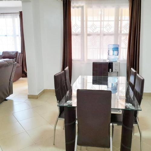 a dining room with a glass table and chairs at Sofitel Executive 4 bedrooms Milimani in Kisumu