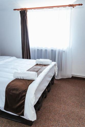 a bedroom with a bed with white sheets and a window at Casa Rosu in Cluj-Napoca
