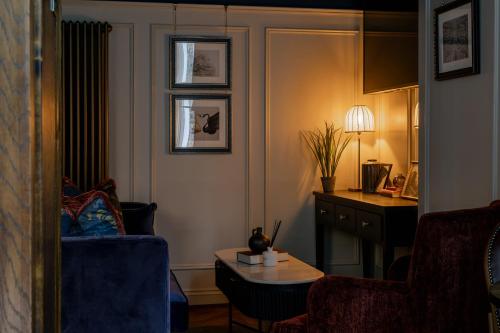 a living room with a blue chair and a table at Worplesdon Place Hotel in Guildford