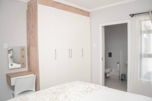 Un dormitorio blanco con una cama y un baño. en Summer Square, Umhlanga Ridge, en Durban