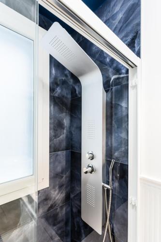 a bathroom with a shower with black tiles at La Bella Vita - In Blu in Sottomarina