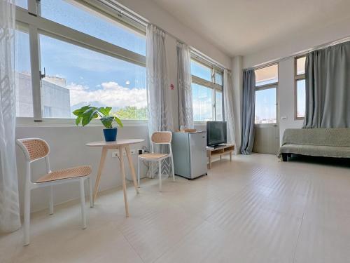 un salon avec une table, des chaises et des fenêtres dans l'établissement 旅人之宿Traveler Inn依預定人數開放房間數, à Hualien