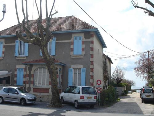 dos autos estacionados frente a una casa con persianas azules en Les Flots Bleus en Andernos-les-Bains