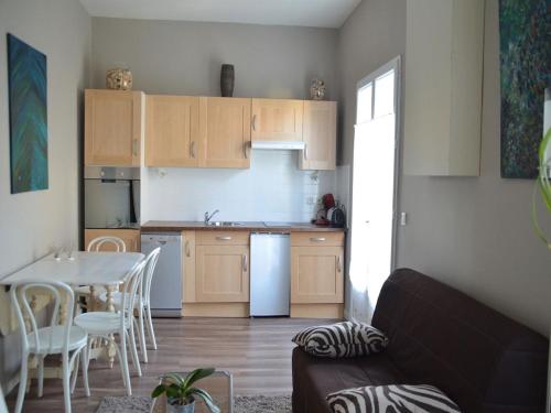 - une cuisine avec des placards en bois, une table, une table et des chaises dans l'établissement Les Flots Bleus, à Andernos-les-Bains