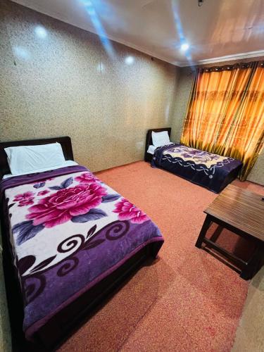 a room with two beds and a table in it at Heaven Hotel Skardu in Skardu
