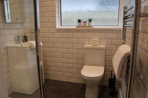 a bathroom with a toilet and a sink and a window at 4 Bedroom Getaway New Forest in New Milton