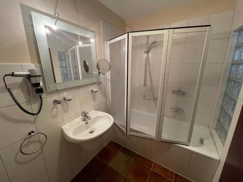a white bathroom with a shower and a sink at Hotel Windflüchter in Breege