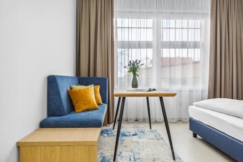 1 dormitorio con silla azul, mesa y ventana en Nena Apartments München City East - NEW OPENING 2024 en Múnich