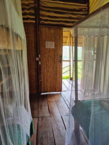 a room with a bed with curtains and a doorway at Mwamba Kelele Lodge in Fort Portal