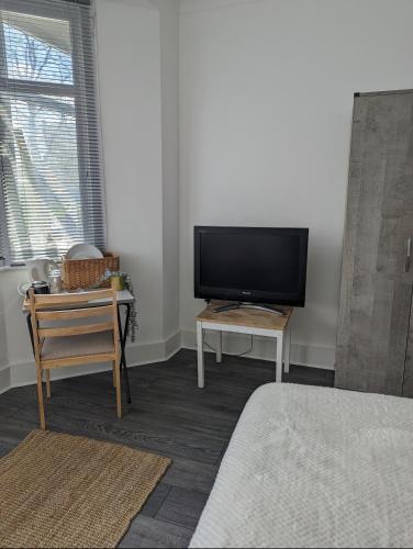 uma sala de estar com uma televisão de ecrã plano e uma mesa em Tottenham Stadium Rooms em Londres