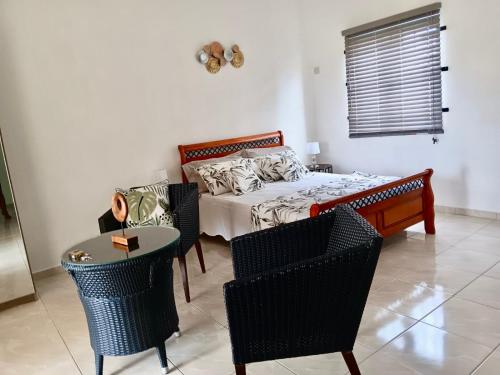 a bedroom with a bed and chairs and a table at Sea La Vie Villa in Grand Gaube