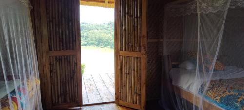 a bedroom with an open door to a window at Mwamba Kelele Lodge in Fort Portal