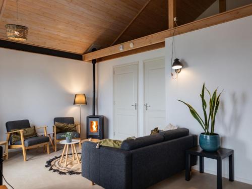 uma sala de estar com um sofá e um tecto de madeira em Cozy chalet with palet stove em De Veenhoop