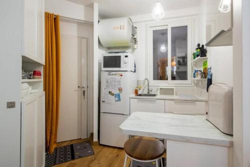 une cuisine avec un réfrigérateur blanc et un comptoir dans l'établissement Appartement cosy avec terrasse, à Paris