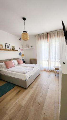 a bedroom with a white bed and wooden floors at Casa Barcelli Sport & Family Apartments in Nago-Torbole