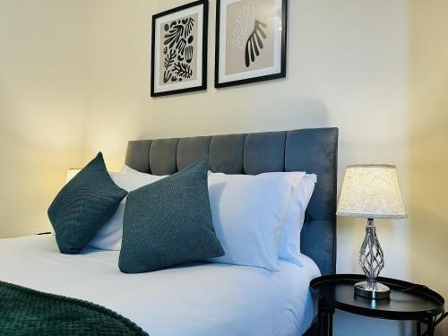 a bed with white pillows and a lamp on a table at Falcon - 2 Bedroom Ground floor flat in Central London in London