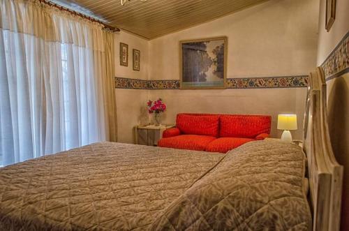 1 dormitorio con 1 cama y 1 sofá rojo en A Casa da Fazenda, en Santo Antônio do Pinhal