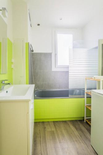 La salle de bains verte est pourvue d'une baignoire et d'un lavabo. dans l'établissement Le Balcon - 2 Chambres, à Brive-la-Gaillarde