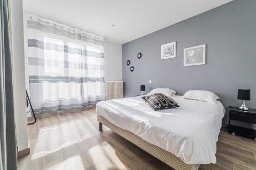 une chambre avec un grand lit blanc et une fenêtre dans l'établissement Le Balcon - 2 Chambres, à Brive-la-Gaillarde