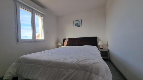 a white bedroom with a bed and a window at Le Mas de la Tortue (Toit Terrasse) in Caromb