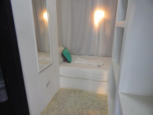 Habitación blanca pequeña con cama y espejo en POSADA RANCHO DELFIN, en El Yaque