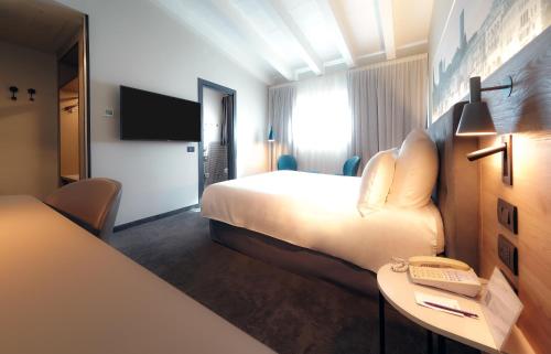 a hotel room with a bed and a desk with a phone at Mercure Bergamo Centro Palazzo Dolci in Bergamo
