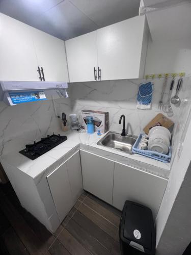 a small kitchen with white cabinets and a sink at ¡Hostal Villa Lobos! in Mocambito