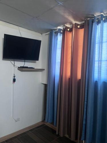 a room with blue curtains and a flat screen tv at ¡Hostal Villa Lobos! in Mocambito