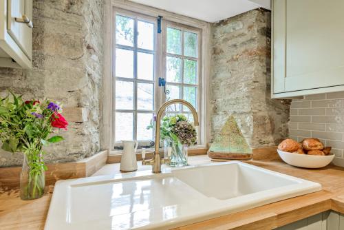 eine Küche mit einer weißen Spüle und einem Fenster in der Unterkunft Cottages in Tranquil Hamlet in Salcombe